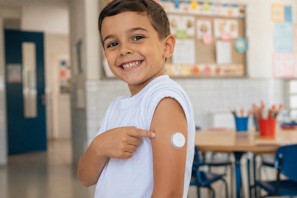 Criança mostrando o sensor de glicemia no braço